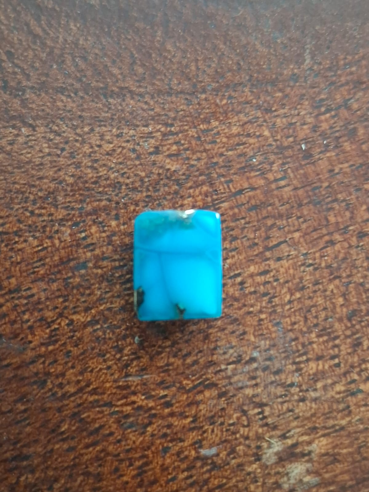 Turquoise stone on a brown wooden surface